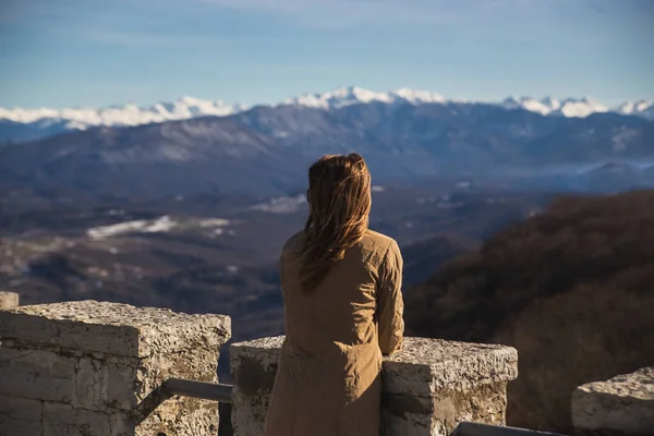 Bir kadın, Akhun Sochi Dağı 'ndaki kulenin gözlem güvertesindeki Kafkasya' nın karlı dağlarına bakıyor.