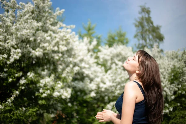 Spring mood, cute woman smell flowering trees, enjoying nature, white floral garden, apple trees warm clear good weather