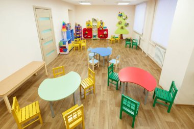 Anaokulundaki sınıflar için masaları olan açık pembe oyun odası.