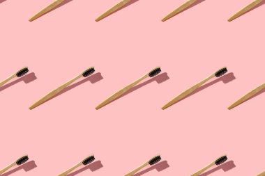 Pembe arka planda bambu diş fırçasıyla süzülen kusursuz desen. Yukarıdaki düz kopya alanından görüntüle