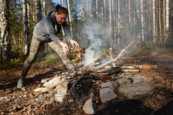 Mädchen entzündet Feuer zum Kochen im Frühlingswald — Stockfoto