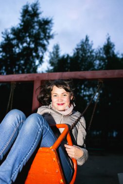 Güzel genç kız enerjik ve zevkle salıncakta sallanıyor.