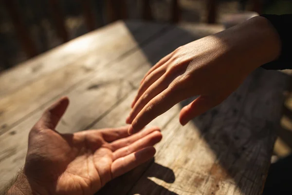 Abrazando las manos de los amantes en la mesa de madera en el día soleado — Foto de Stock