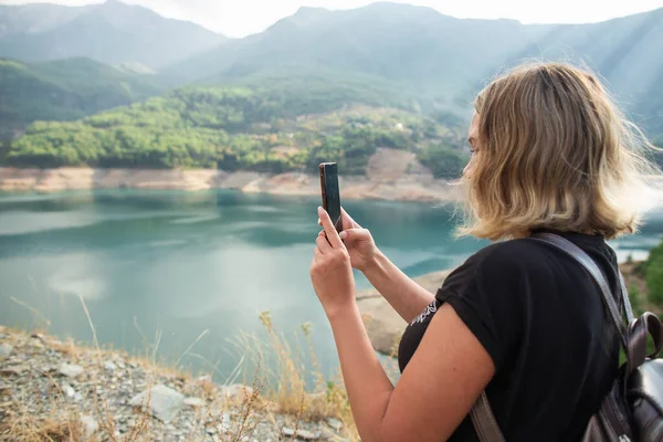 Touriste prend des photos sur le lac téléphone dans les montagnes — Photo