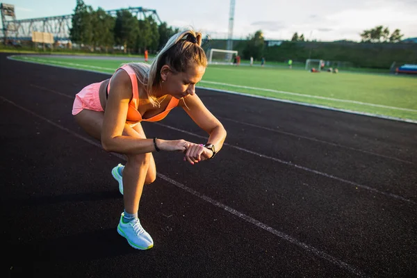 Sportovní dívka začne trénovat na chytré hodinky před závodem na stadionu — Stock fotografie