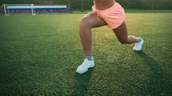 Fitness dívka ve sportovních trenýrkách a špičkový trénink na trávě na stadionu. Koncepce tréninku a odpočinku — Stock fotografie