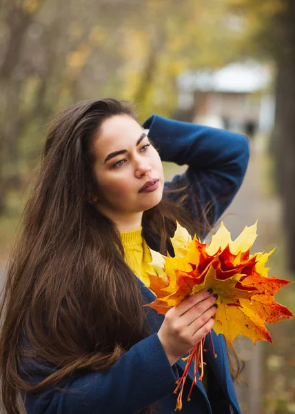 Junge Frau mit Herbstblättern in der Hand und Herbst gelben Ahorn Garten Hintergrund — Stockfoto
