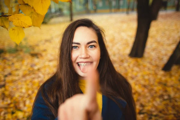 Playful young woman with autumn leaves in hand and fall yellow maple garden background — Stock Photo, Image