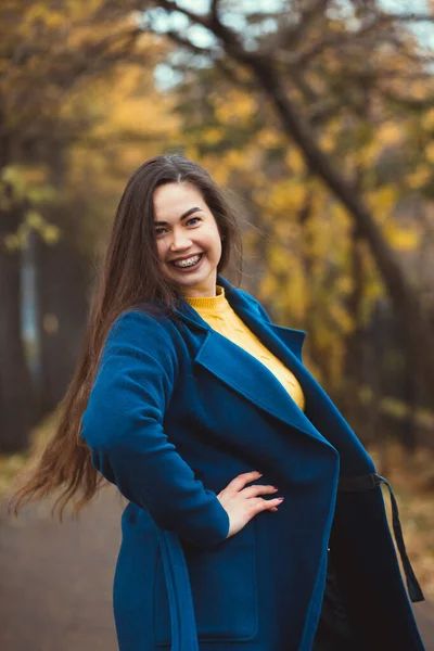 Mujer joven juguetona con hojas de otoño en la mano y el fondo amarillo otoño jardín de arce — Foto de Stock