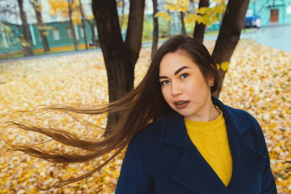 Mujer joven juguetona con hojas de otoño en la mano y el fondo amarillo otoño jardín de arce — Foto de Stock