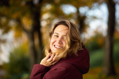Sonbahar parkında sonbahar sarısı yapraklarının keyfini çıkaran neşeli genç bir kadın. İnsanlar, duygular, mevsimlik flört konsepti