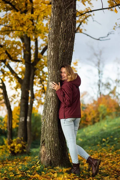 Игривая молодая женщина наслаждается осенью желтыми листьями в осеннем парке. Люди, чувства, понятие свидания — стоковое фото