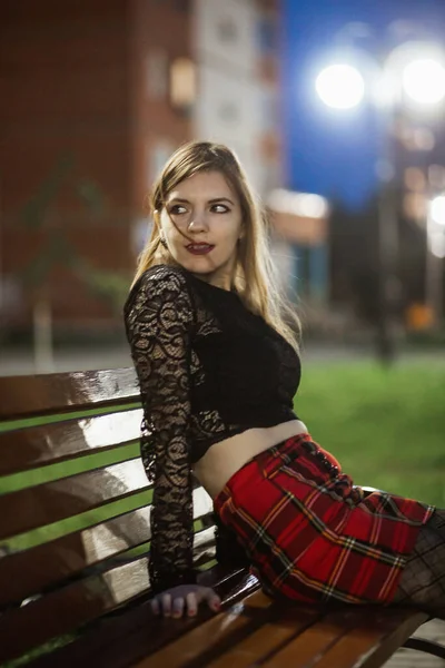 Érzéki fiatal nő piros kockás szoknyában éjszaka városi fények — Stock Fotó