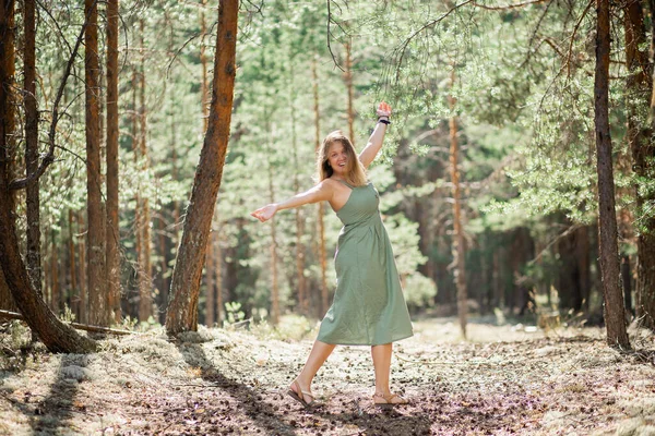 Uma menina bonita com cabelo voador em uma floresta de pinheiros. Boa bruxa da floresta em um vestido verde — Fotografia de Stock