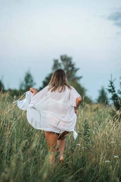 穿着半透明的白色长袍的迷人姑娘在草地上嬉闹着调情 — 图库照片