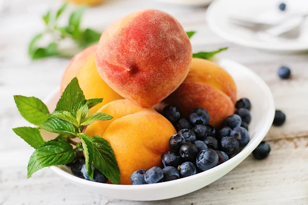 Färska persikor och blåbär i skål — Stockfoto