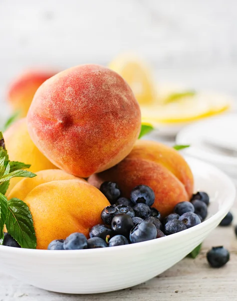 Färska persikor och blåbär i skål — Stockfoto