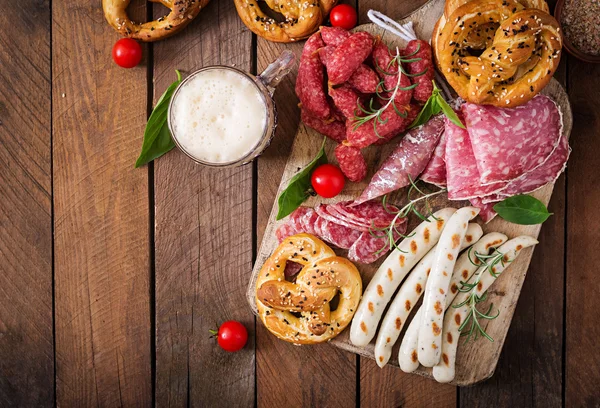 Copo de cerveja, pretzels e várias salsichas — Fotografia de Stock