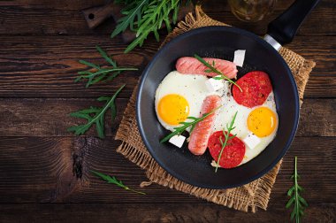 İngiliz kahvaltısı. Yağda yumurta, sosis, domates ve peynir. Amerikan yemeği. Üst görünüm, genel görünüm, kopyalama alanı