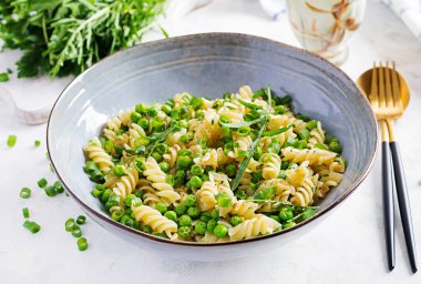 Vejetaryen salatası. Yeşil bezelye ve soğanlı Fusilli makarna. İtalyan yemeği..