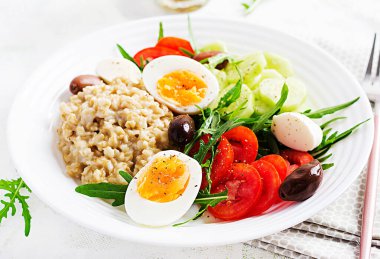 Kahvaltı yulaf lapası, Yunan salatası, salatalık, zeytin ve yumurta. Sağlıklı dengeli yiyecekler.