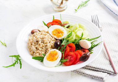 Kahvaltı yulaf lapası, Yunan salatası, salatalık, zeytin ve yumurta. Sağlıklı dengeli yiyecekler.