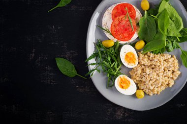 Kahvaltı yulaf lapası haşlanmış yumurta, domatesli sandviç, roka ve ıspanak. Sağlıklı yiyecekler. Üst görünüm, genel görünüm, kopyalama alanı