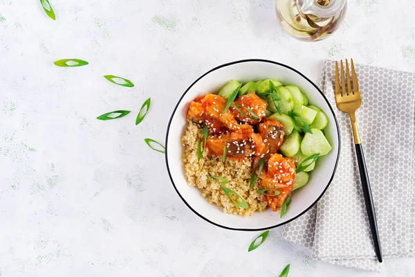 Fish fillet cooked in tomato sauce with bulgur and cucumber on a plate on a light background. Healthy eating concept. Easy cooking. Top view, flat lay, copy space