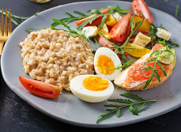 早餐燕麦粥与煮熟的鸡蛋 鲑鱼三明治和西红柿沙拉 健康食品 — 图库照片