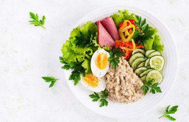 Kahvaltı yulaf lapası haşlanmış yumurta, jambon ve sebze salatası. Sağlıklı yiyecekler. Üst görünüm, genel görünüm, kopyalama alanı