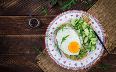 Sağlıklı kahvaltı. Noel brunch 'ı. Avokado sandviçi, sahanda yumurta ve ahşap masada roka ile salatalık. Üst görünüm, alanı kopyala