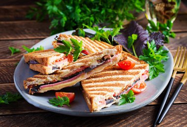 Jambon, domates, peynir ve yaprak hardallı ızgara sandviç sandviçi. Lezzetli kahvaltı ya da atıştırmalık.