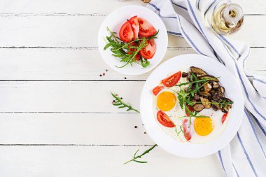 Lezzetli kahvaltı. Yağda yumurta, orman mantarı, domates ve roka. Öğle yemeği. Üst görünüm, genel görünüm, kopyalama alanı