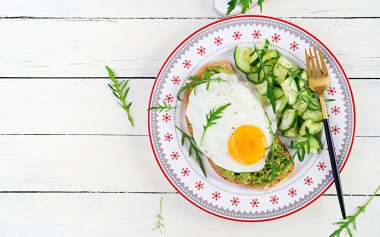 Sağlıklı kahvaltı. Noel brunch 'ı. Yağda yumurtalı avokado sandviçi ve sağlıklı kahvaltı ya da atıştırmalık olarak roka salatalıklı taze salata. Üst görünüm, alanı kopyala