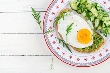 Sağlıklı kahvaltı. Noel brunch 'ı. Yağda yumurtalı avokado sandviçi ve sağlıklı kahvaltı ya da atıştırmalık olarak roka salatalıklı taze salata. Üst görünüm, alanı kopyala