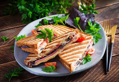 Jambon, domates, peynir ve yaprak hardallı ızgara sandviç sandviçi. Lezzetli kahvaltı ya da atıştırmalık.