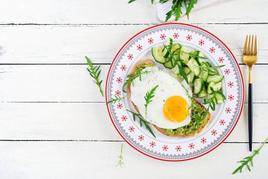 Sağlıklı kahvaltı. Noel brunch 'ı. Yağda yumurtalı avokado sandviçi ve sağlıklı kahvaltı ya da atıştırmalık olarak roka salatalıklı taze salata. Üst görünüm, alanı kopyala