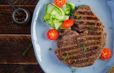 Izgara, sulu, orta pişmiş, baharatlı biftek ve taze salata. Üst görünüm, genel görünüm, düz görünüm