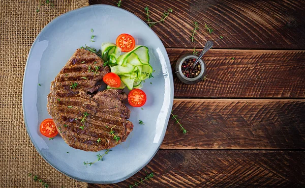 Izgara, sulu, orta pişmiş, baharatlı biftek ve taze salata. Üst görünüm, genel görünüm, düz görünüm