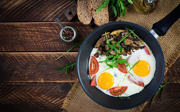 Lezzetli kahvaltı. Yağda yumurta, orman mantarı, domates ve roka. Öğle yemeği. Üst görünüm, genel görünüm, kopyalama alanı