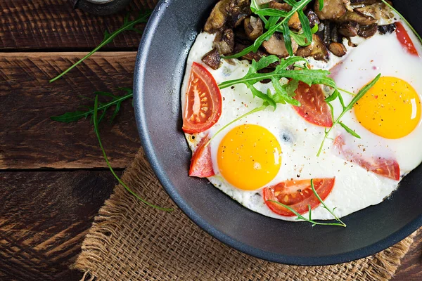 Lezzetli kahvaltı. Yağda yumurta, orman mantarı, domates ve roka. Öğle yemeği. Üst görünüm, genel görünüm, kopyalama alanı
