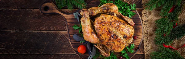 Baked turkey or chicken. The Christmas table is served with a turkey, decorated with bright tinsel. Fried chicken, table setting. Christmas dinner. Top view, banner, copy space