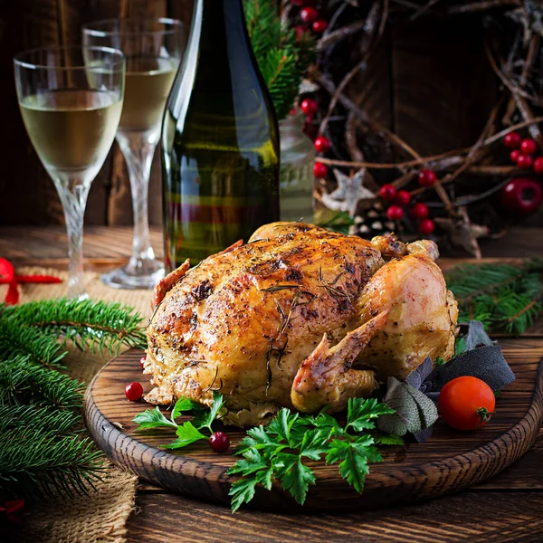 Baked turkey or chicken. The Christmas table is served with a turkey, decorated with bright tinsel. Fried chicken, table setting. Christmas dinner.