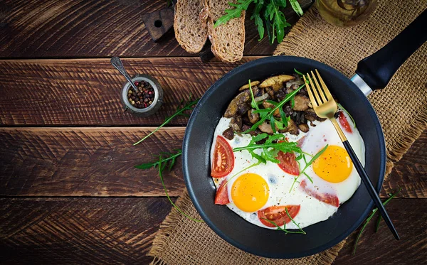 Lezzetli kahvaltı. Yağda yumurta, orman mantarı, domates ve roka. Öğle yemeği. Üst görünüm, genel görünüm, kopyalama alanı