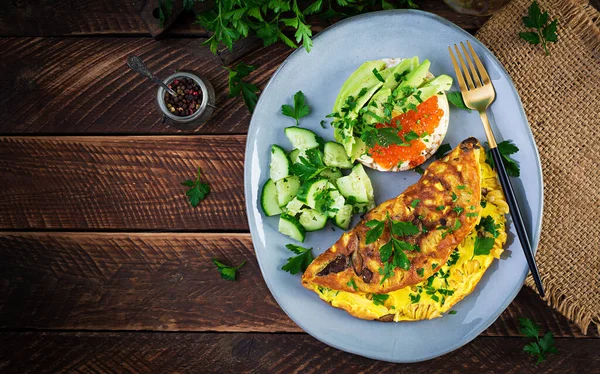 Omelette with forest mushroom, fusilli pasta and sandwich wich red caviar, avocado on plate. Frittata - italian omelet. Top view, overhead, copy space — Stock Image Omelette Forest Mushroom Fusilli Pasta Sandwich Wich Red Caviar Avocado Stock Photo