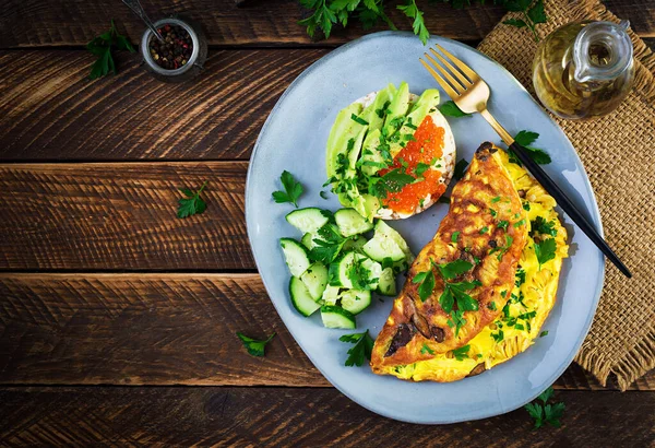 Omelette with forest mushroom, fusilli pasta and sandwich wich red caviar, avocado on plate. Frittata - italian omelet. Top view, overhead, copy space — Stock Image Omelette Forest Mushroom Fusilli Pasta Sandwich Wich Red Caviar Avocado Royalty Free Stock Images