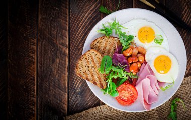 İngiliz kahvaltısı - kızarmış yumurta, fasulye, domates, sosis, jambon ve tost. Üst görünüm, düz görünüm, genel görünüm