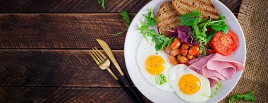 İngiliz kahvaltısı - kızarmış yumurta, fasulye, domates, sosis, jambon ve tost. Üst manzara, afiş, genel giderler