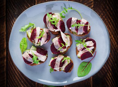 Ringa filetosu. Tuzlu ringa balıklı sandviç ve ahşap masadaki tostların üzerinde pancar kökü. İskandinav mutfağı. Üst görünüm, genel görünüm