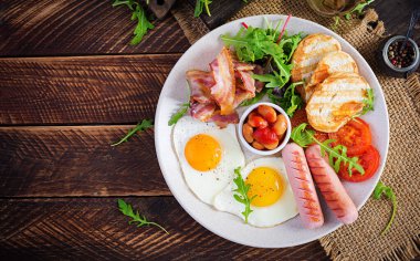 İngiliz kahvaltısı - kızarmış yumurta, fasulye, domates, sosis, pastırma ve tost. Üst görünüm, düz görünüm, genel görünüm